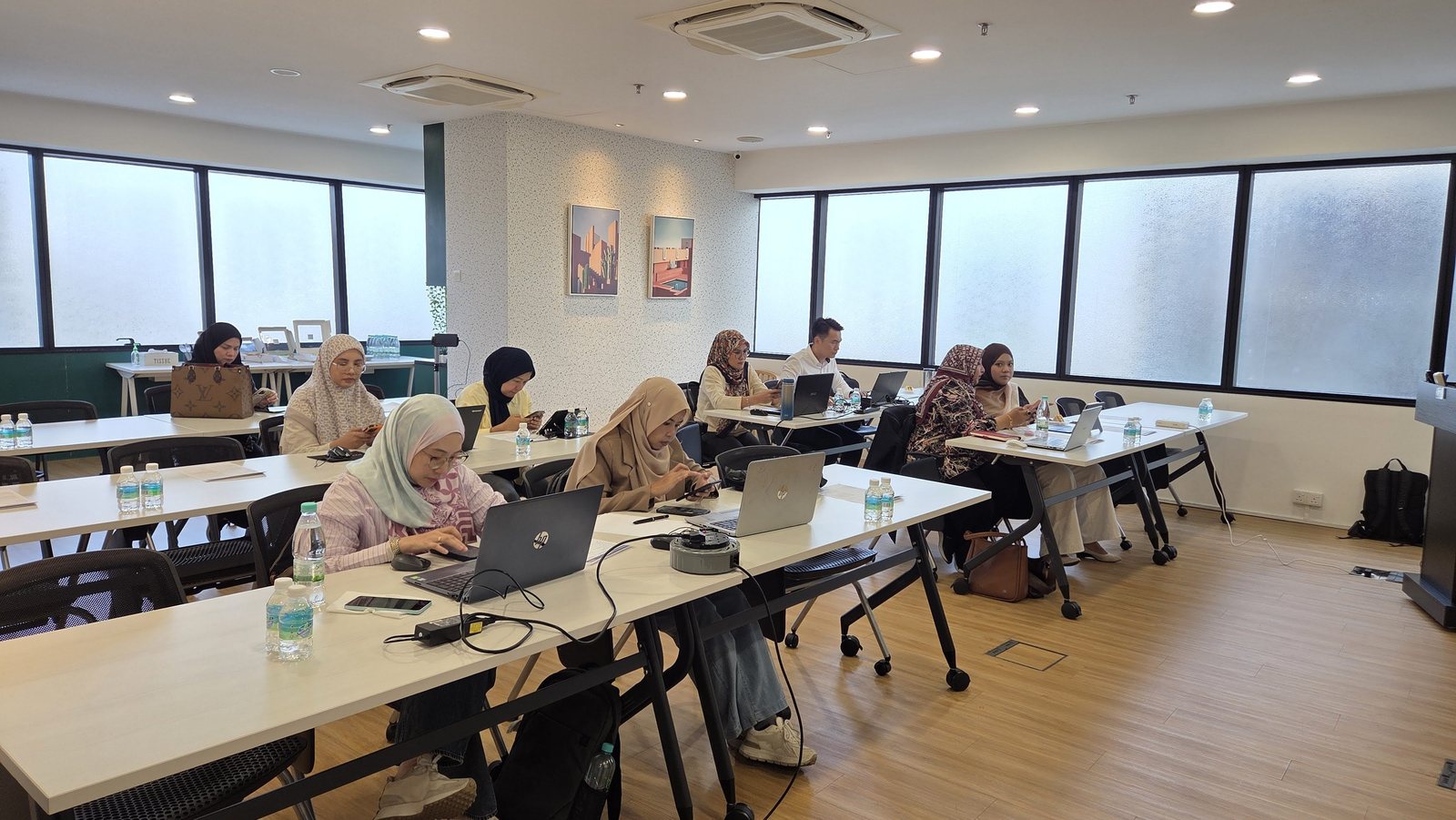 Bilik seminar dengan peserta di meja panjang menggunakan laptop